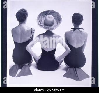 Rückansicht von drei weiblichen Modemodellen in Badeanzügen, zwei knienden Schwimmflossen und einer sitzend mit Strohhut, keine Position, 1950. (Foto: Toni Frissell Collection Stockfoto
