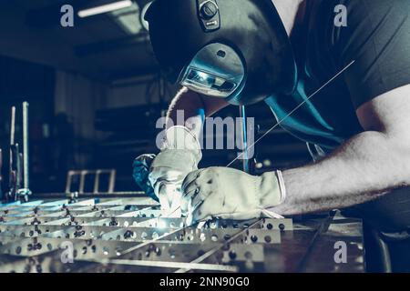 Professioneller Kaukasierschweißer im Schutzhelm während des WIG-Schweißprozesses. Thema Metallverarbeitende Industrie. Stockfoto