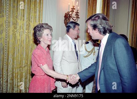 Präsident Ronald Reagan und Nancy Reagan begrüßen Donald Trump (rechts) im State Dining Room des Weißen Hauses während eines Empfangs für Eureka College Stipendiaten, Washington, DC, 8/4/1983. (Foto vom Fotobüro des Weißen Hauses Stockfoto