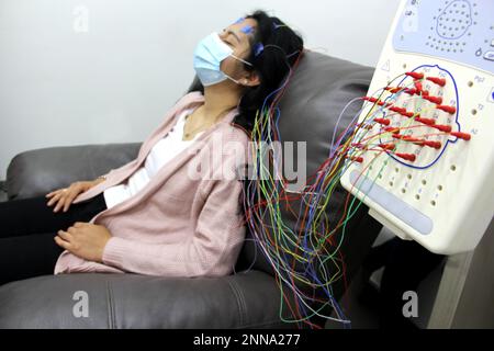 Lateinische Frau mit Schutzmaske in medizinischen Tests, Elektroenzephalogramm und Hirnkartierung in Zeiten der Covid-19-Kontingenz Stockfoto