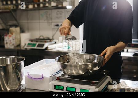 Eine Köchin arbeitet in einer modernen Industrieküche. Der Vorgang der Zubereitung von Kuchen in einer Bäckerei oder einem Café. Stockfoto