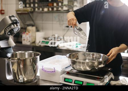 Eine Köchin arbeitet in einer modernen Industrieküche. Der Vorgang der Zubereitung von Kuchen in einer Bäckerei oder einem Café. Stockfoto