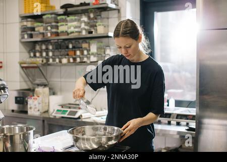 Eine Köchin arbeitet in einer modernen Industrieküche. Der Vorgang der Zubereitung von Kuchen in einer Bäckerei oder einem Café. Stockfoto