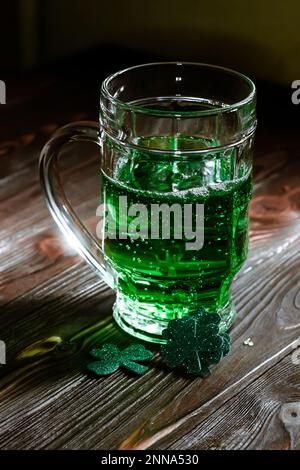 Ein Glas Bier auf einer Party, wo St. Patricks Tag. Gebrühter Schnaps für ein veraltetes Patrick's. Tasse mit grünem Alkohol in einem Pub auf einem Jahrgang Stockfoto