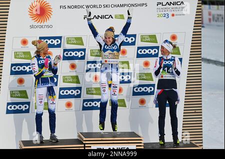 Schwedens Ebba Andersson springt vor Freude auf das Podium, nachdem er am 25. Februar 2023 bei den FIS Nordic Ski World Championships 2023 in Planica, Slowenien, den Skiathlon gewonnen hat. Zu ihrer Rechten: Frieda Karlsson, zweitplatzierte Finisher; zu ihrer Linken, Astrid Oeyre Slind, Norwegen, drittplatzierte Finisher. Stockfoto