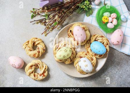 Osterkomposition. Süßes italienisches Osterbrot klingelt von Blätterteig und gefärbten Eiern auf Steinhintergrund. Blick von oben. Stockfoto