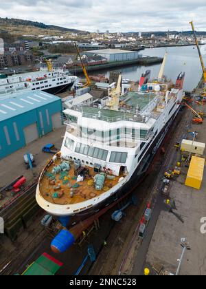 Greenock, Schottland, Großbritannien. 25. Februar 2023 Die Glen-Sannox-Fähre wird im Trockendock von Greenock gesehen, wo sie ausgestattet wird. Drei weitere Caledonian MacBrayne-Fähren, die ebenfalls nebenan repariert und gewartet werden, sind die Isle of Lewis, die Caledonian Isles und der MV Loch Fyne. Diese Fähren sind derzeit außer Betrieb für Calmac. Iain Masterton/Alamy Live News Stockfoto