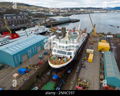 Greenock, Schottland, Großbritannien. 25. Februar 2023 Die Glen-Sannox-Fähre wird im Trockendock von Greenock gesehen, wo sie ausgestattet wird. Drei weitere Caledonian MacBrayne-Fähren, die ebenfalls nebenan repariert und gewartet werden, sind die Isle of Lewis, die Caledonian Isles und der MV Loch Fyne. Diese Fähren sind derzeit außer Betrieb für Calmac. Iain Masterton/Alamy Live News Stockfoto