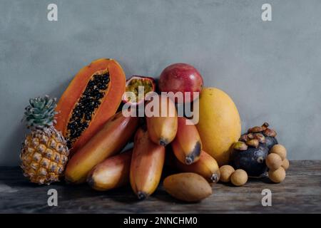 Stillleben mit asiatischen Früchten. Ein Set bunter Früchte. Dunkles natürliches Licht für Fotos. Stockfoto