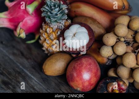 Stillleben mit asiatischen Früchten. Ein Set bunter Früchte. Dunkles natürliches Licht für Fotos. Stockfoto