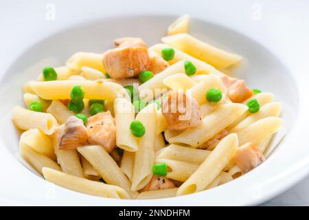 Pasta Penne mit Lachs und grünen Erbsen Stockfoto