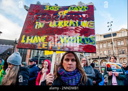 Während der Demonstration wird ein ukrainischer Flüchtling mit einem Plakat gesehen. In Amsterdam Tausende ukrainische Menschen und Anhänger gingen vom Museumplein zum Dam-Platz, um die niederländische Gesellschaft daran zu erinnern, dass der Krieg weitergeht und dass mutige ukrainische Menschen ihr Land verteidigen und dass die Ukraine damit Unterstützung braucht.denn Freitag, der 24. Februar, ist ein Jahr, seit Russland seine Existenz begonnen hat Krieg gegen die Ukraine, mehrere Demonstrationen sind in den Niederlanden geplant. Mehr als acht Millionen Menschen wurden gezwungen, die Ukraine zu verlassen, und weitere fünf Millionen wurden intern vertrieben. Stockfoto