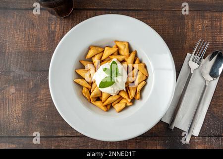 Frittierte knusprige türkische Ravioli oder Manti auf einer weißen Porzellanplatte Stockfoto