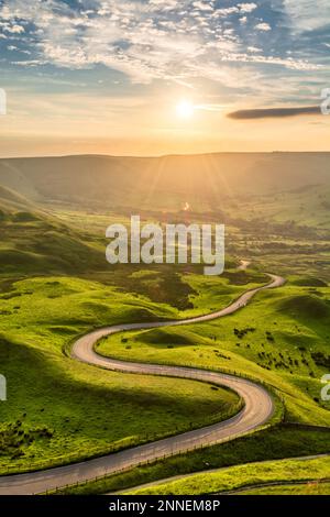 Gewundene Landstraße führt nach Edale im English Peak District mit wunderschönem goldenen Licht, das durch das Tal scheint. Stockfoto