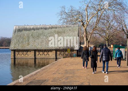 An einem sonnigen Wintertag im Hyde Park, London, England, könnt ihr am Serpentine Recreational Lake spazieren gehen und ein altes Bootshaus besichtigen Stockfoto