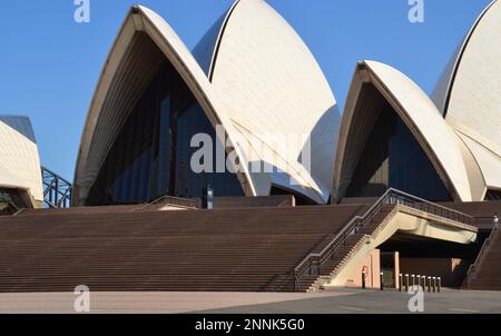 Berühmte weiße gewölbte Dachbögen des Opernhauses von Sydney in Australien mit den weitläufigen Stufen im Vordergrund an einem heißen, sonnigen Morgen Stockfoto