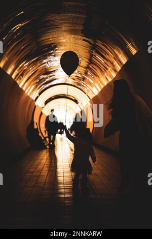 Die Silhouette eines Kindes im beleuchteten Tunnel Stockfoto