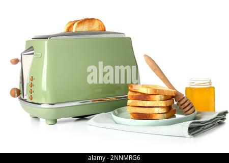 Moderner Toaster mit Brotscheiben, einem Glas Honig und leckeren Toasts auf weißem Hintergrund Stockfoto