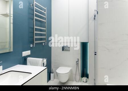 Badezimmer in Blau und Weiß mit Toilette, großem Spiegel, Duschkabine, Beleuchtung und Waschbecken. Sauberes und frisches Bad mit modernem Licht. Geräumiger Schläger Stockfoto