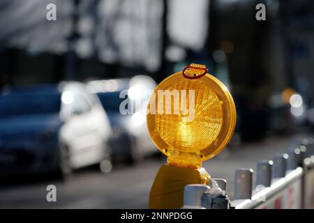 Beleuchtete Baustellenbeleuchtung auf einem Absperrgitter einer Straßenbaustelle vor verschwommenem Hintergrund Stockfoto