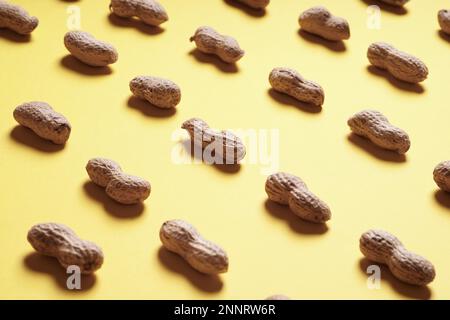 - Aus der Nähe Erdnüsse in Tanks in endlosen Reihen auf gelbes Papier Hintergrund angeordnet - selektive Fokus Stockfoto