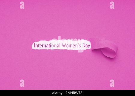 Internationaler Tag der Frauen wird am 8. März - Text vom Loch in rosa Papier Hintergrund zerrissen offenbart gefeiert. Stockfoto