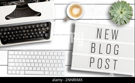 Blogging Konzept, Ansicht von oben Text neuen Blog-eintrag auf Leuchtkasten auf Tabelle mit alten Schreibmaschine, Computer Tastatur und Tasse Kaffee Stockfoto