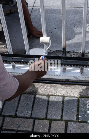 Maler retuschiert das elektrische Tor der Eigentumswohnung Garage in Weiß. Stockfoto