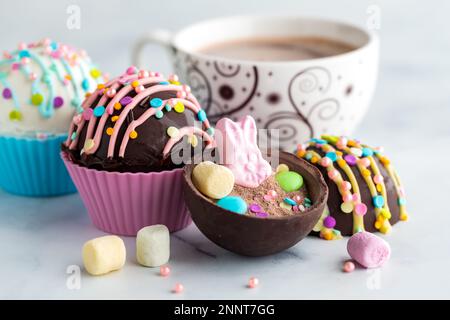 Osterbomben mit heißer Schokolade und einer Tasse Kakao dahinter. Stockfoto