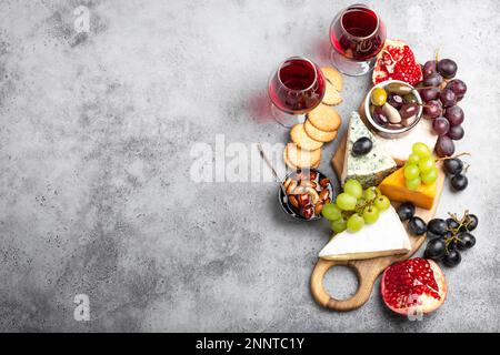 Auswahl an Käse und Vorspeisen, Wein in Gläsern, Camembert, Brie, Cheddar, cracker, Trauben, Nüsse, Honig. Verschiedene Käsemischungen auf rustikalem Holz Stockfoto