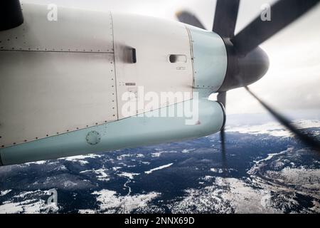 Foto eines Regionalflugzeugs mit Turboprop-Propeller, das im Winter über British Columbia fliegt. Stockfoto