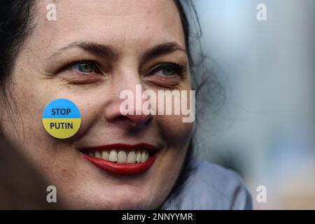 Brüssel, Belgien. 25. Februar 2023. Eine Demonstrantin zeigt auf ihrer Wange einen Aufkleber mit der Aufschrift "Stop Putin" während eines Protests anlässlich des einjährigen Jahrestages der russischen Invasion der Ukraine in Brüssel, Belgien, am 25. Februar 2023. (Kreditbild: © Valeria Mongelli/ZUMA Press Wire) NUR REDAKTIONELLE VERWENDUNG! Nicht für den kommerziellen GEBRAUCH! Stockfoto