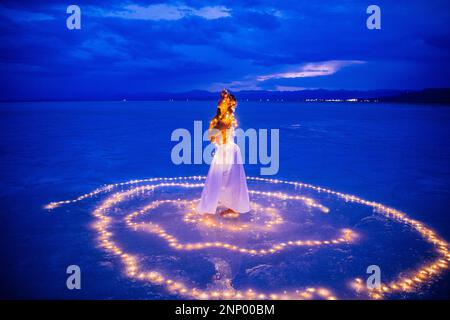 Eine Tänzerin, umgeben von einem Lichtkreis auf dem Wasser Stockfoto