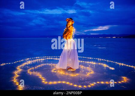 Eine Tänzerin, umgeben von einem Lichtkreis auf dem Wasser Stockfoto