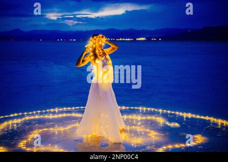 Eine Tänzerin, umgeben von einem Lichtkreis auf dem Wasser Stockfoto