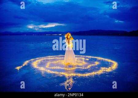 Eine Tänzerin, umgeben von einem Lichtkreis auf dem Wasser Stockfoto