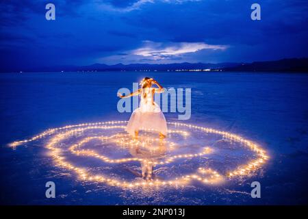 Eine Tänzerin, umgeben von einem Lichtkreis auf dem Wasser Stockfoto