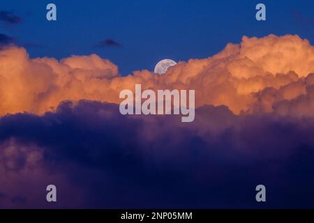 Violette Wolken und Vollmond bei Sonnenuntergang Stockfoto