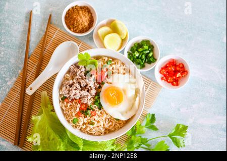 Nudelschüssel mit gekochtem Ei Hackfleisch Schweinefleisch Gemüse Frühlingszwiebeln Zitrone Limette Salat Sellerie und Chili auf dem Tisch Essen, Instantnudeln kochen leckeres Essen Stockfoto