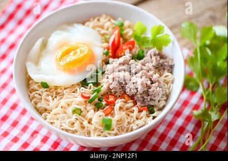 Nudelschüssel mit gekochtem Ei Hackfleisch Schweinefleisch Gemüse Frühlingszwiebeln Zitrone Limette Salat Sellerie und Chili auf dem Tisch Essen, Instantnudeln kochen leckeres Essen Stockfoto