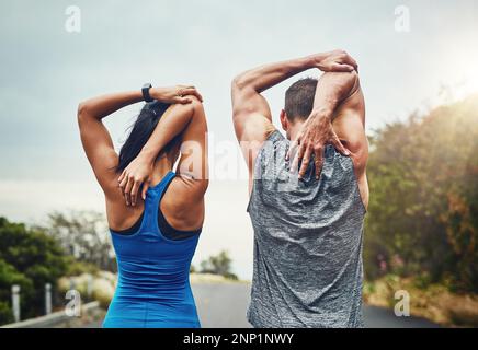 Wir dehnen uns zusammen und trainieren dann. Ein unbekanntes Paar, das für einen Marathon im Freien trainiert. Stockfoto