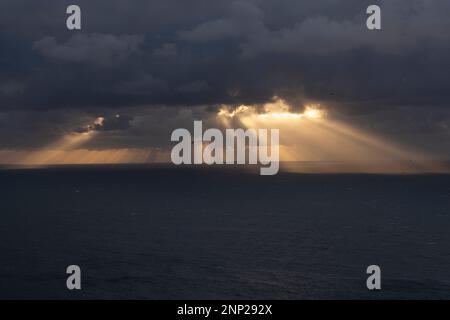 Die Sonne strahlt von den Wolken über dem Meer Stockfoto