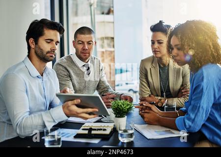 Werfen Sie einen Blick darauf... eine Gruppe von Kollegen, die während eines Meetings im Sitzungssaal ein Tablet verwenden. Stockfoto