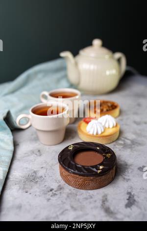 Törtchen mit Füllungen auf dem Tisch. Chchaynik, Tassen und Törtchen im Café. Stockfoto