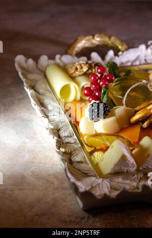 Gemischter Käse auf einem Tablett mit Nüssen und Honig. Stockfoto