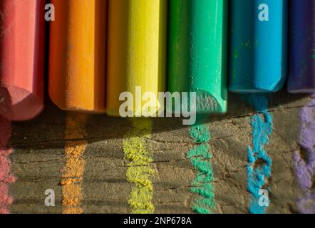 Nahaufnahme von farbigen Kreiden, die die lgtbi-Regenbogenflagge auf gealtertem Holz bilden Stockfoto