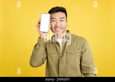 Ein glücklicher chinese, der ein Handy mit leerem Bildschirm hält Stockfoto