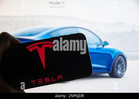 Rheinbach, Deutschland 26. Februar 2023, das Markenlogo des Automobilherstellers „Tesla“ auf dem Display eines Smartphones vor der Website Stockfoto