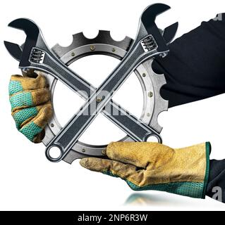 Arbeiter mit Arbeitshandschuhen, der ein metallisches Zahnrad (Metallgetriebe) mit zwei modernen verstellbaren Schraubenschlüsseln aus Edelstahl hält, isoliert auf weiß. Stockfoto