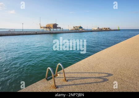 Cesenatico-Kanal, Fischerhütten in Meeresnähe und Stahlleiter im Vordergrund. Emilia Romagna, Provinz Forli Cesena, Italien Stockfoto